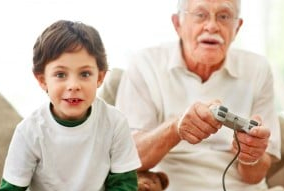 Imagen de un abuelo jugando a videojuegos con su nieto