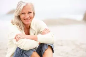 image of woman sitting on the beach smiling